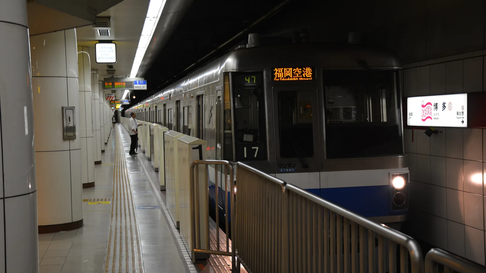 A Fukuoka City Subway train bound for Fukuoka Airport waiting at Hakata Station, with the Hakata station sign on the wall.