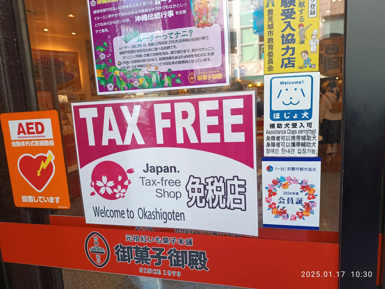 The Japan Tax-free Shop sign on the glass door of a food shop on Kokusai-dori in Naha, with the words 免税店 and Welcome. Photo from January 2025, before the 2026 change.