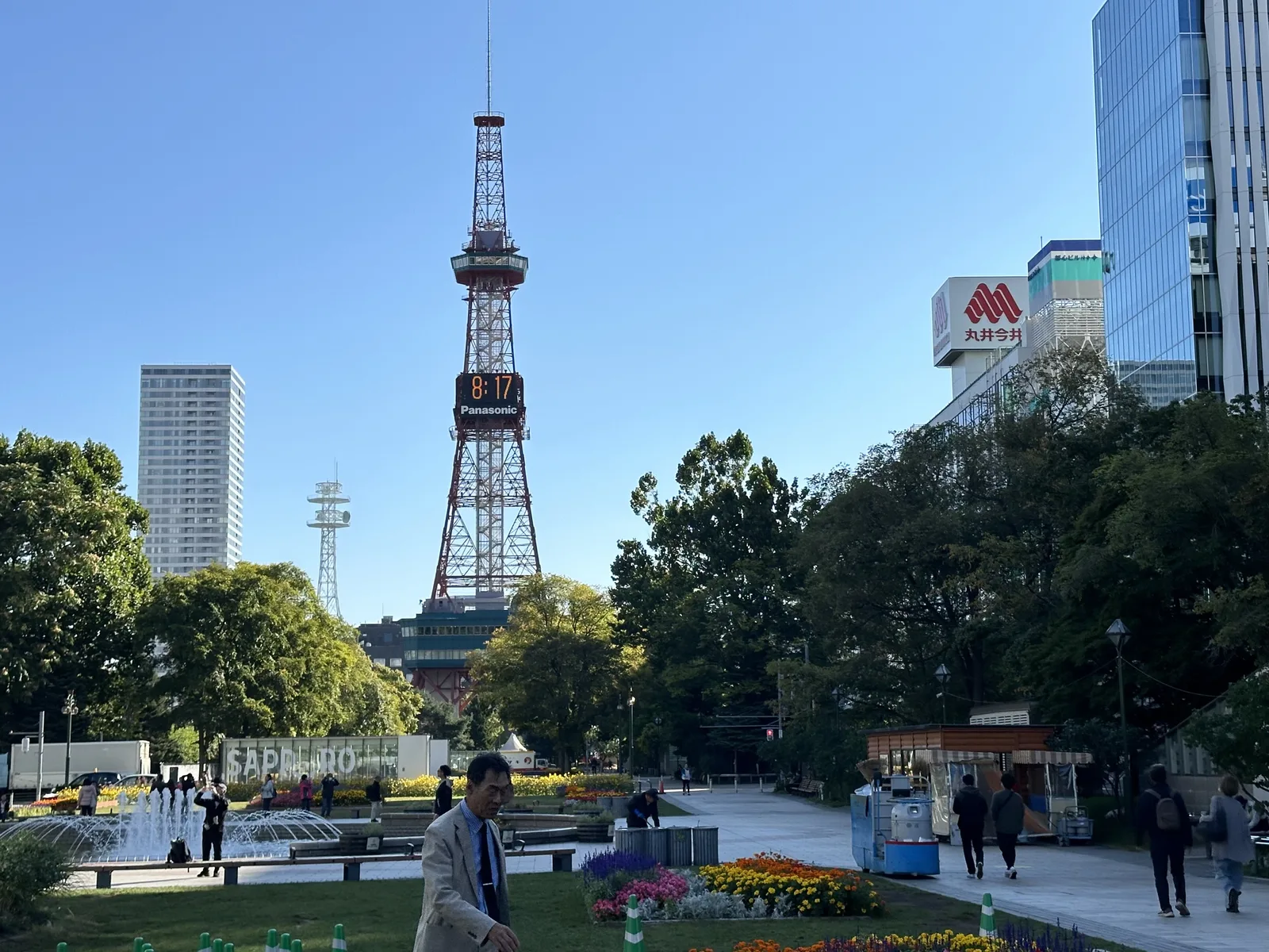 Odori Park in Sapporo, a long, narrow strip of park with trees, flower beds and a fountain plaza, leading toward the Sapporo TV Tower.