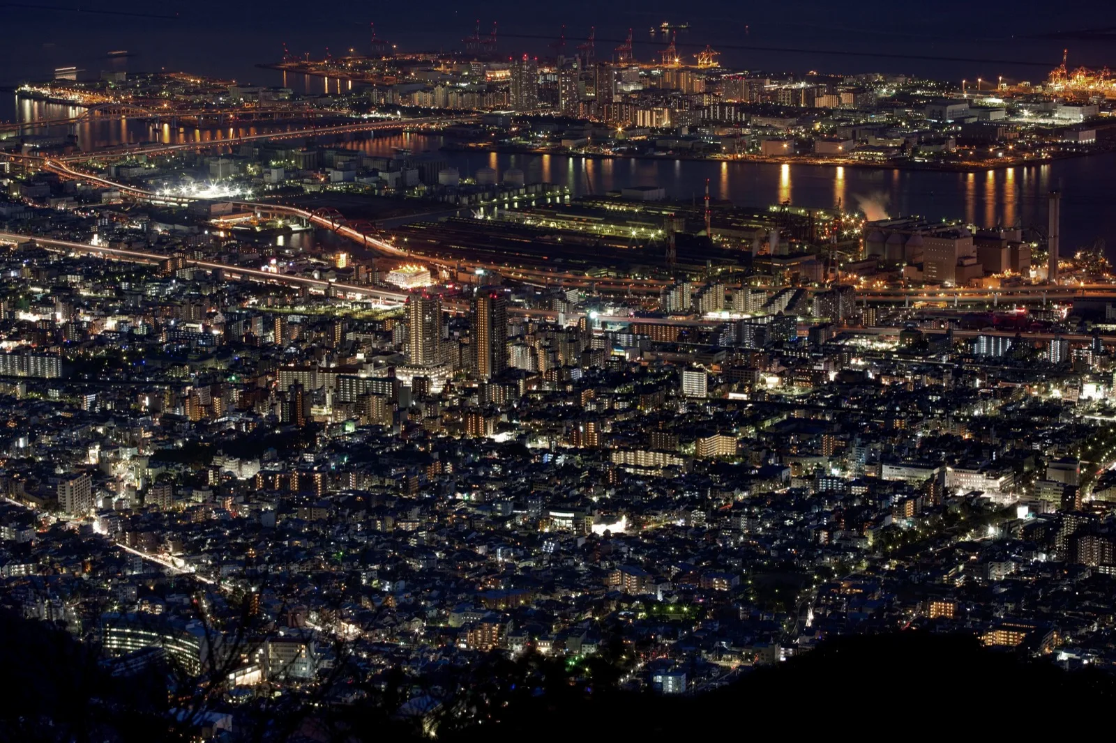 A night view of Rokko Island and Higashinada-ku in Kobe, seen from Mount Maya, with city lights reflecting on the water.